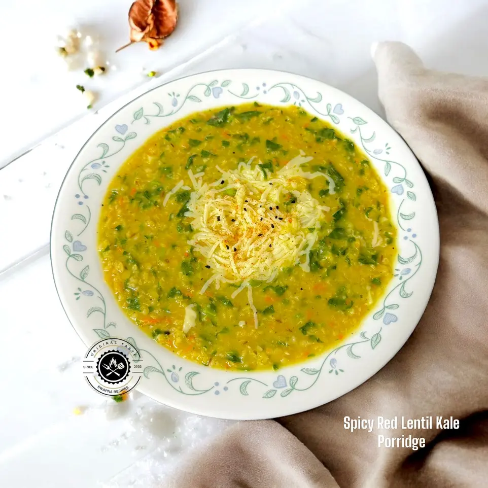 Spicy Red Lentil and Kale Porridge Recipe | Healthy A hearty bowl of spicy red lentil and kale porridge with vegetables, oats, and melted cheese served hot for a nourishing vegan meal.