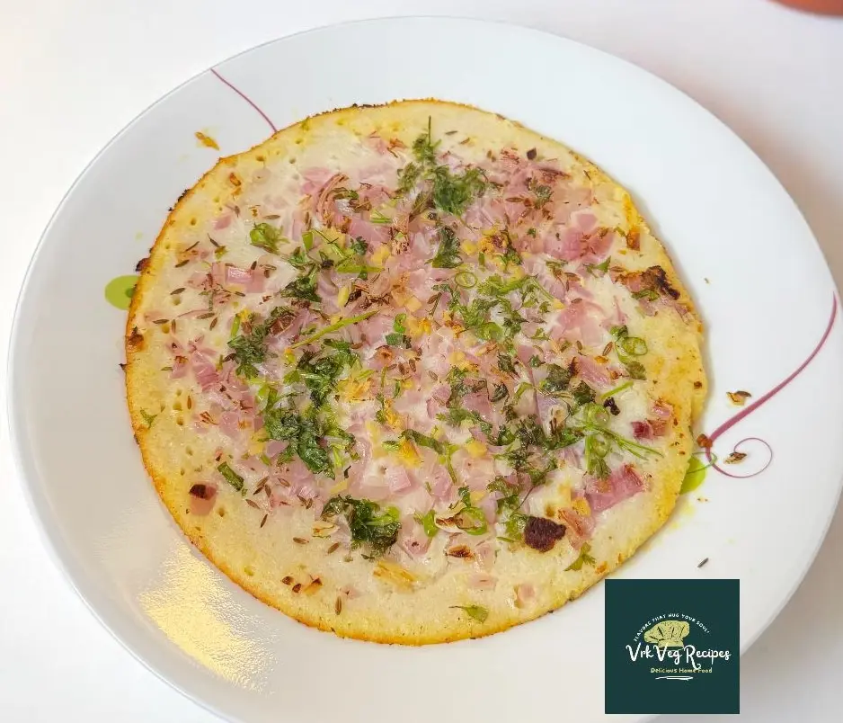 Traditional Indian onion uttapam cooked on tawa and garnished with fresh coriander and jeera.
