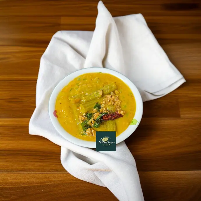 A vibrant bowl of dal with golden garlic tempering, soft drumsticks, and rich Indian spices, served with rice or chapati.