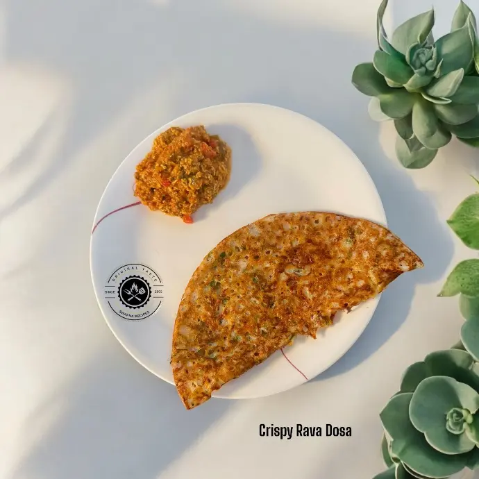 Quick Crispy Rava Dosa Recipe for Lazy Brunches Thin, golden brown instant rava dosa sizzling with cashews, herbs, and curry leaves.