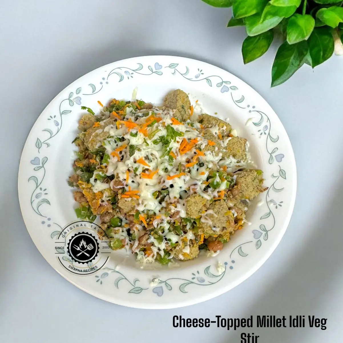 Cheese-topped millet idli stir fry with veggies like capsicum, carrot, and cowpeas—a quick, protein-rich twist on leftover idlis with melted cheese.