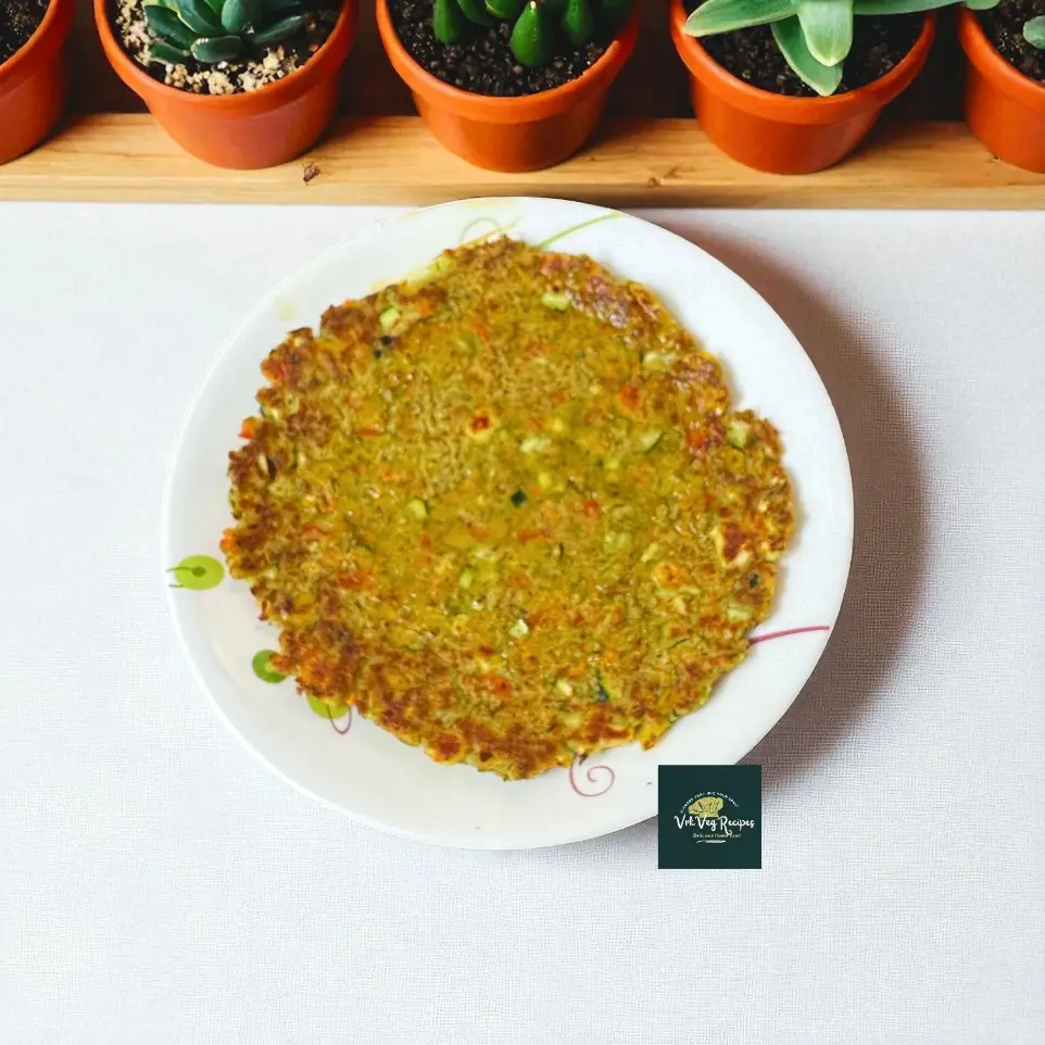 Protein-rich Moong Dal Paneer Chilla with carrots, zucchini, capsicum, spices, and curry leaves, served hot with ghee for a wholesome breakfast."