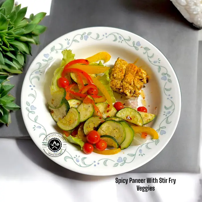 Delicious spicy paneer with stir fry veggies served over lettuce, packed with capsicum, zucchini, broccoli, and cherry tomatoes for a healthy meal.