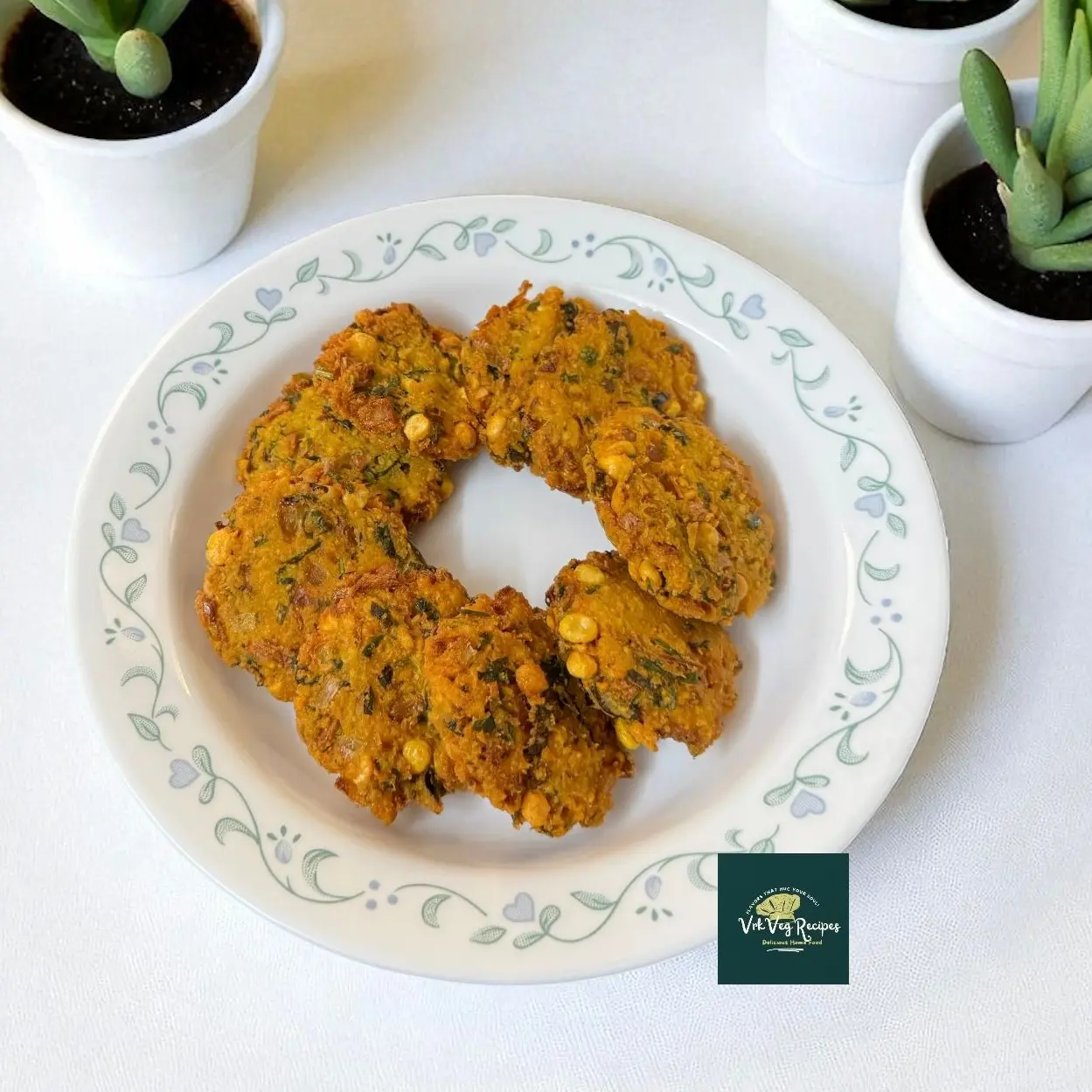 Golden Channa Dal Vada stacked, with curry leaves and onion visible; crispy edges and fluffy centers — South Indian lentil fritters served with coconut chutney.