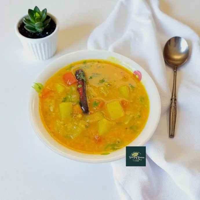 Close-up of hot lauki sambar with dal and tempering of jeera and red chilli, garnished with coriander and cracked pepper, ready for rice or idli.