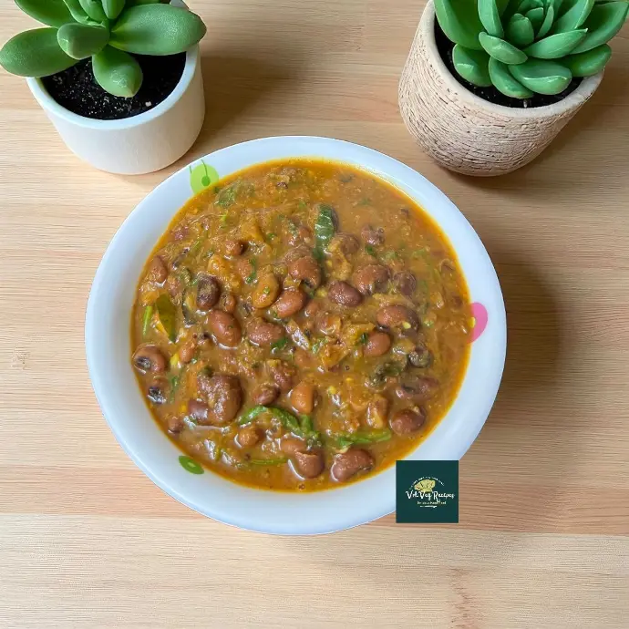 Homestyle red lobia curry in a rustic bowl topped with coriander and curry leaves, showing a thick tomato-onion gravy and perfectly cooked red cowpeas.