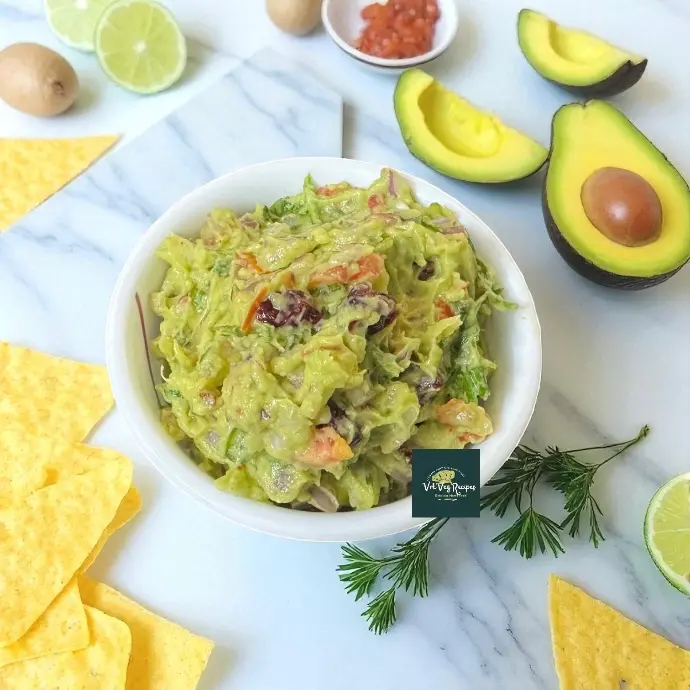 Creamy avocado cranberry salad with chopped onion, tomato, coriander, red chili flakes, and lemon juice served fresh in a bowl.