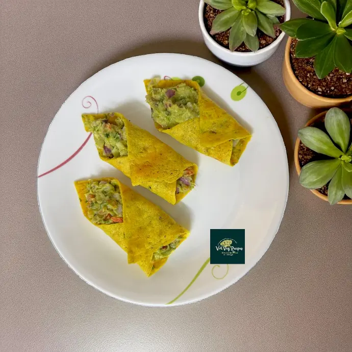 Golden Besan Dosa Rolls with Cranberry Avocado Mash Golden besan dosa rolls stuffed with tangy avocado and sweet cranberries, garnished with fresh microgreens for a delicious treat.