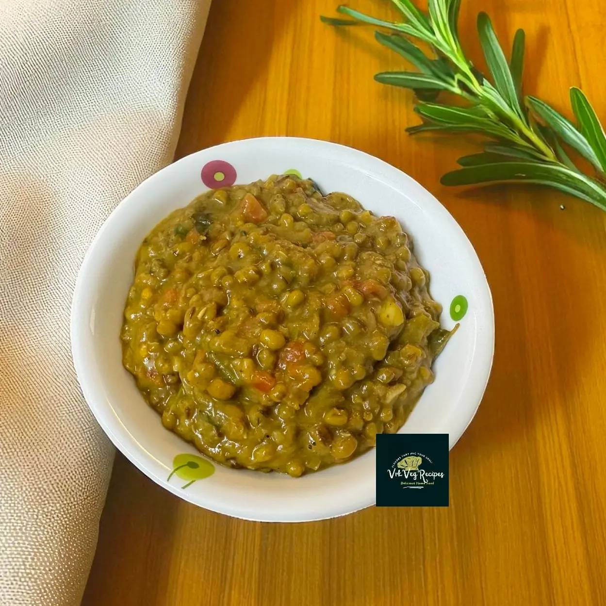 Steaming green moong dal masala in a bowl, garnished with fresh coriander, ghee tempering of cumin, crushed garlic and a red chilli, ready to eat.