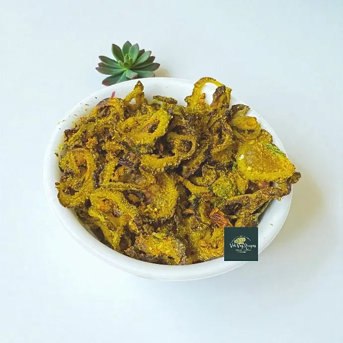 Crispy kakarakaya dry coconut fry with golden fried bitter gourd slices tossed in roasted coconut and spices, served with a fresh lemon squeeze.