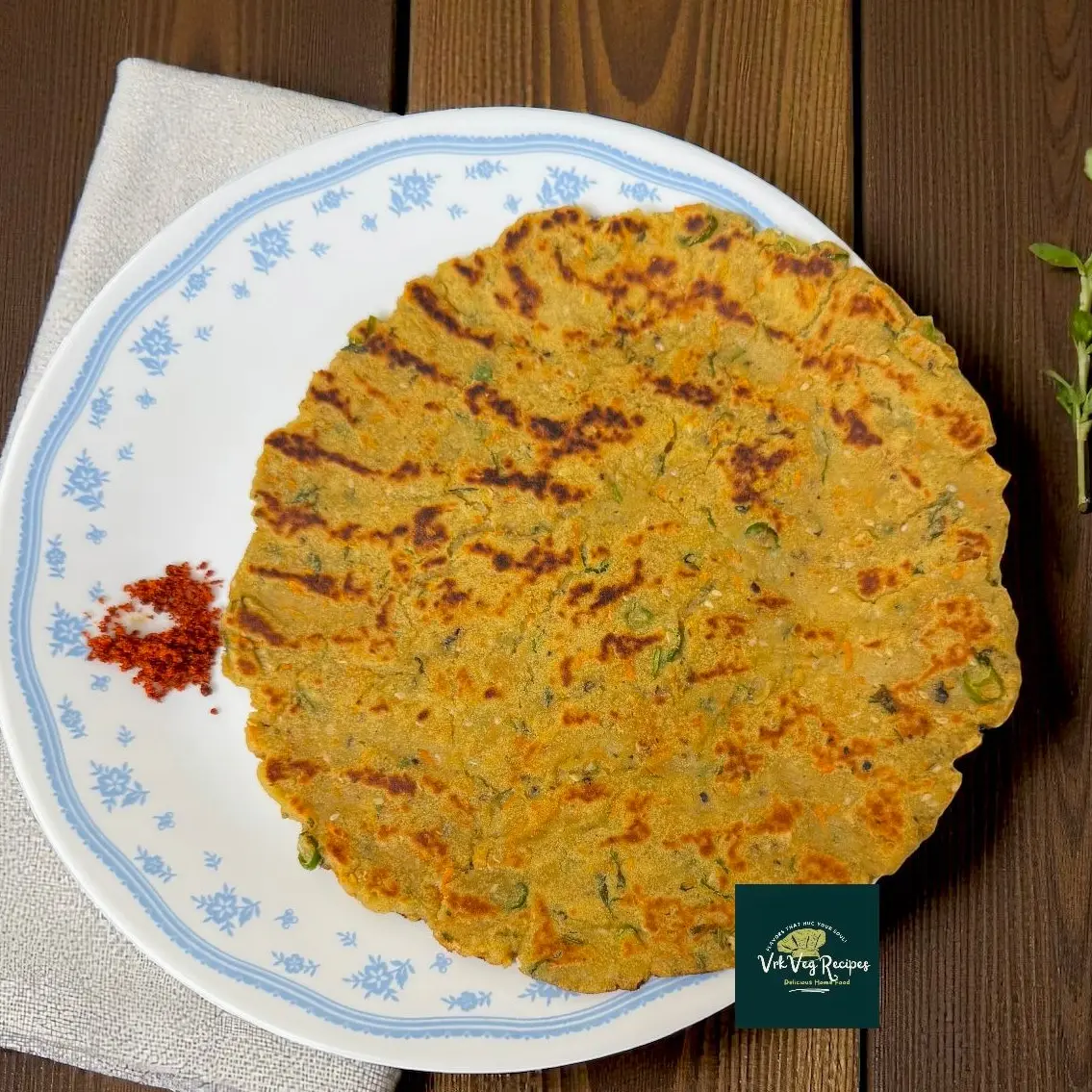 Top view of golden Sweet Potato Amaranth Rotta on a plate, showing sesame seeds, grated carrot specks and coriander garnish — rustic gluten-free flatbread.