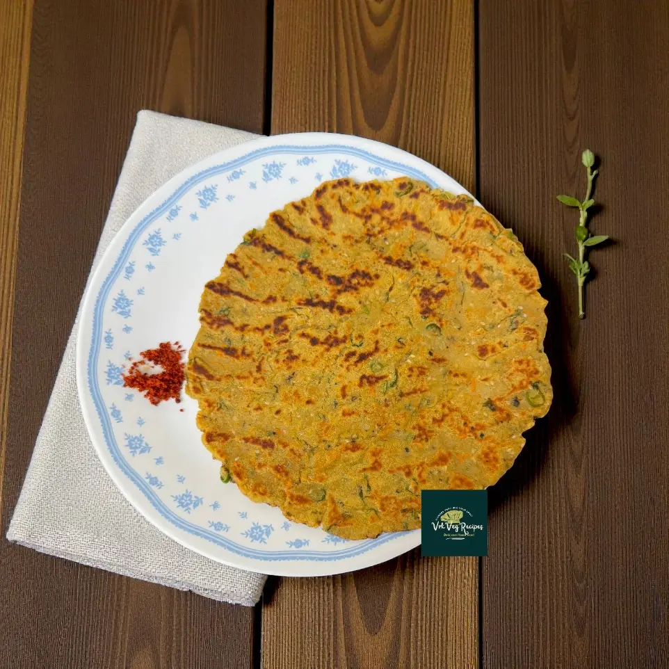 Close-up of crisp Amaranth-Sweet Potato Rotta on a tawa, browned edges and sesame seeds, with chopped green chillies and coriander sprinkled.